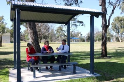 Inglewood Lions Club President Erin Fleming and Secretary Wondah Lollback sitting at a new picnic shelter in the Inglewood Lions Park with the Hon Cr Lawrence Springborg  AM